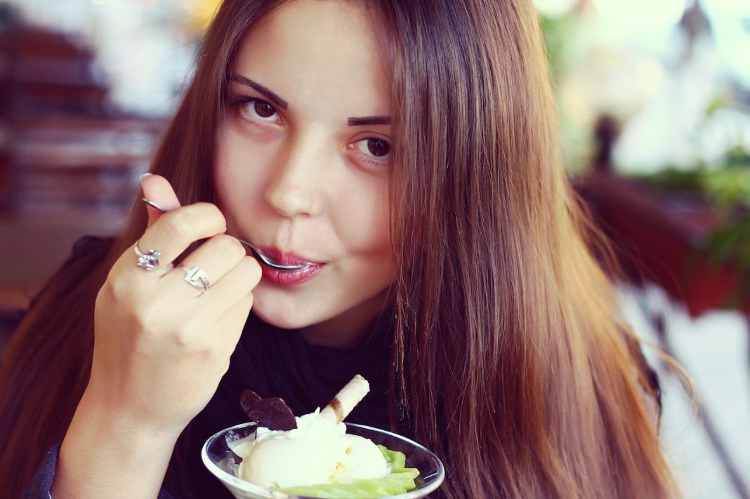 young beautiful woman eating a dessert of kiwi
